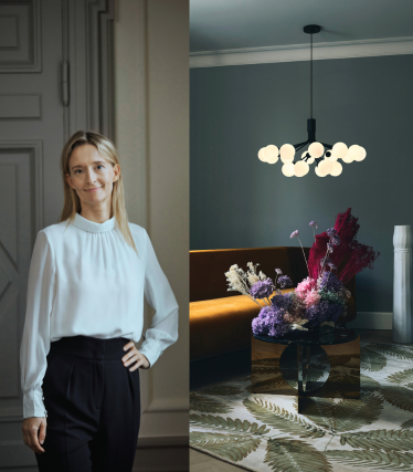 Portrait de la designer Sofie Refer à côté d'une suspension lumineuse Nuura dans un intérieur stylé aux accents floraux.